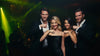 Four friends in a nightclub tasting caviar from the backs of their hands